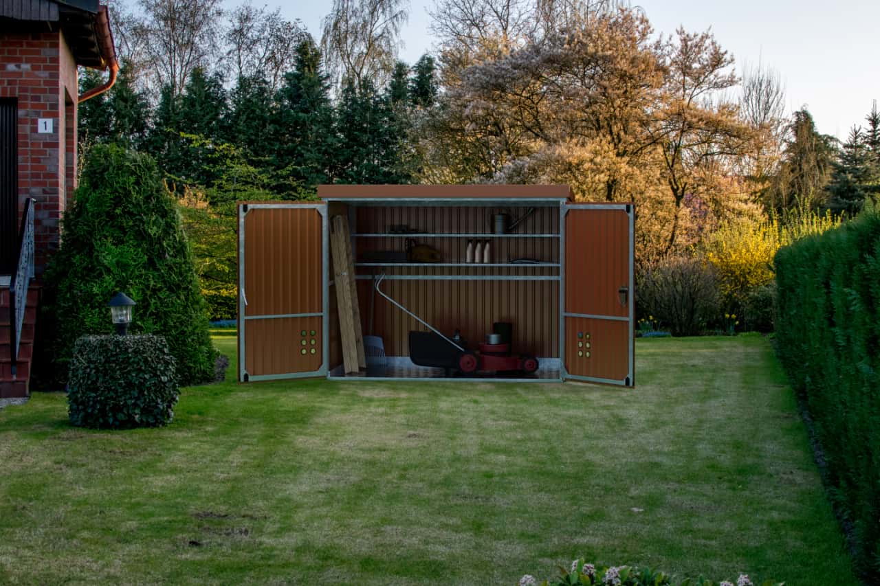 Braune Fertiggarage nahe der Grundstücksgrenze, mit offenem Tor auf grünem Rasen